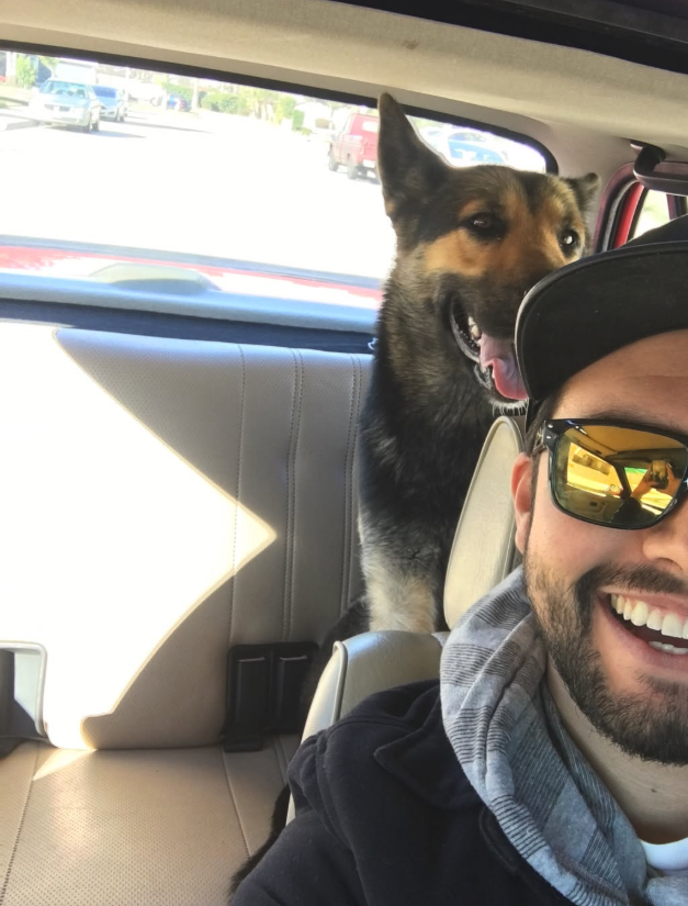 Gio smiling with his German Shepherd Lola in the back seat of the red BMW E30