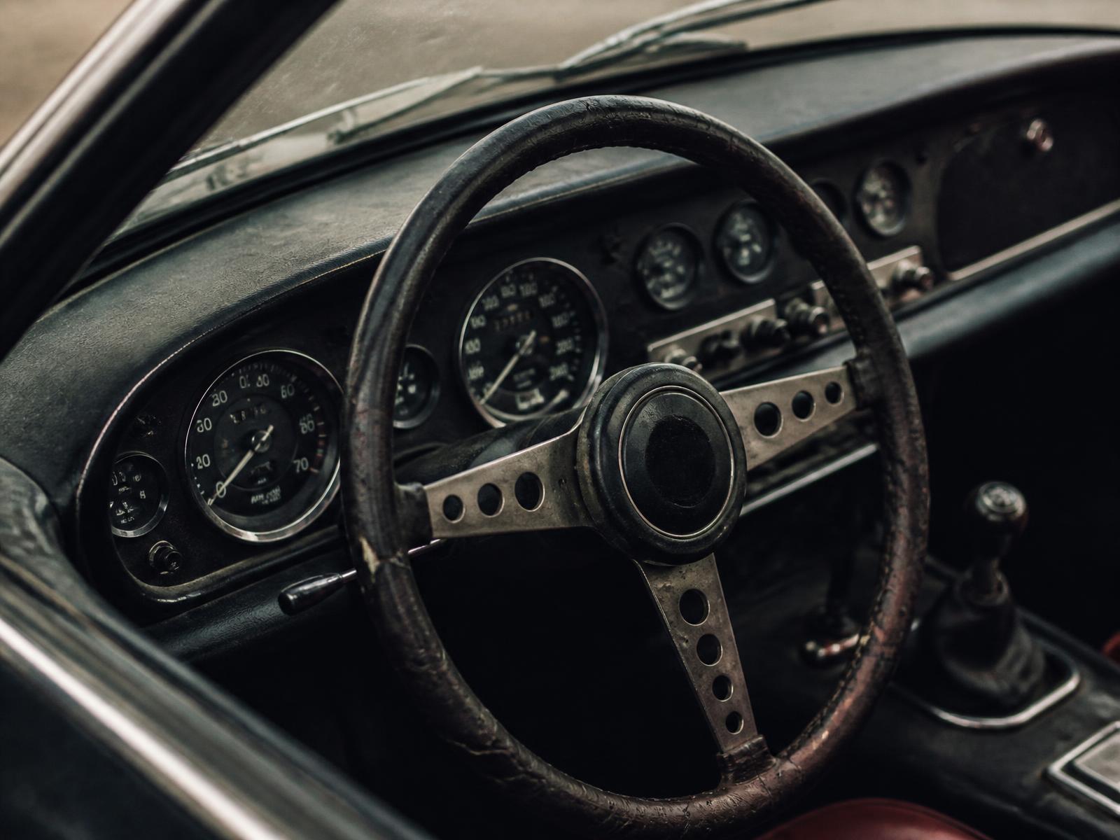 Worn leather steering wheel and analogue gauges in an old car