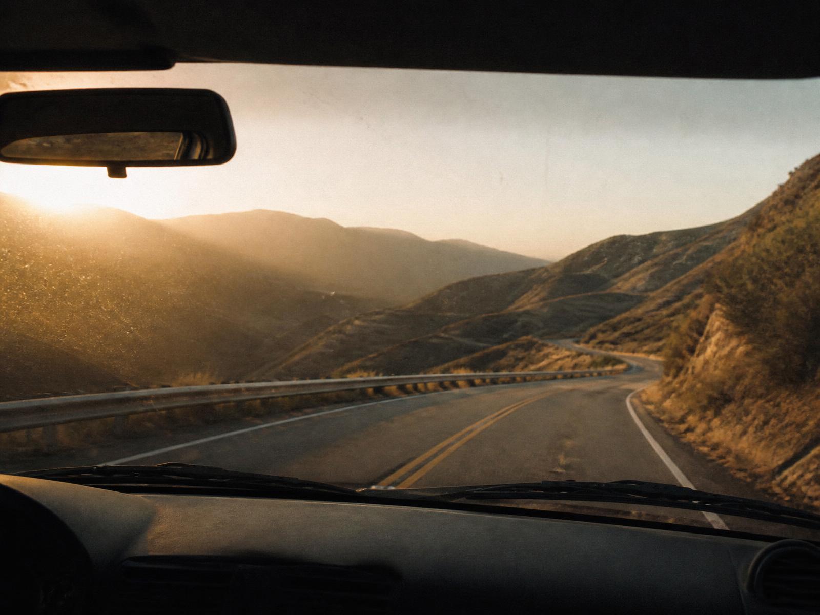Canyon road seen through a dusty windshield at golden hour